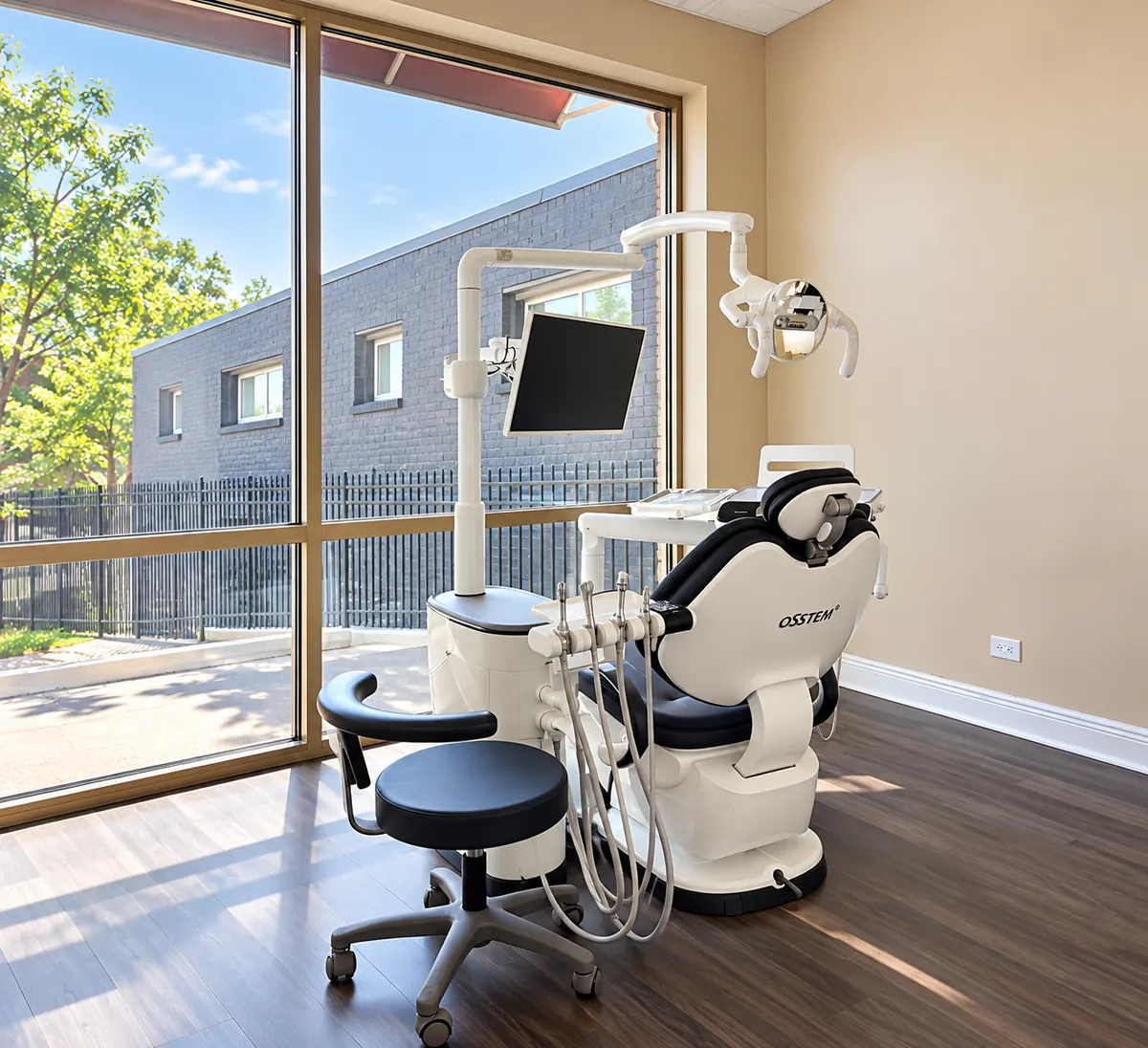 Treatment room with a dental chair beside a large window with a view of trees